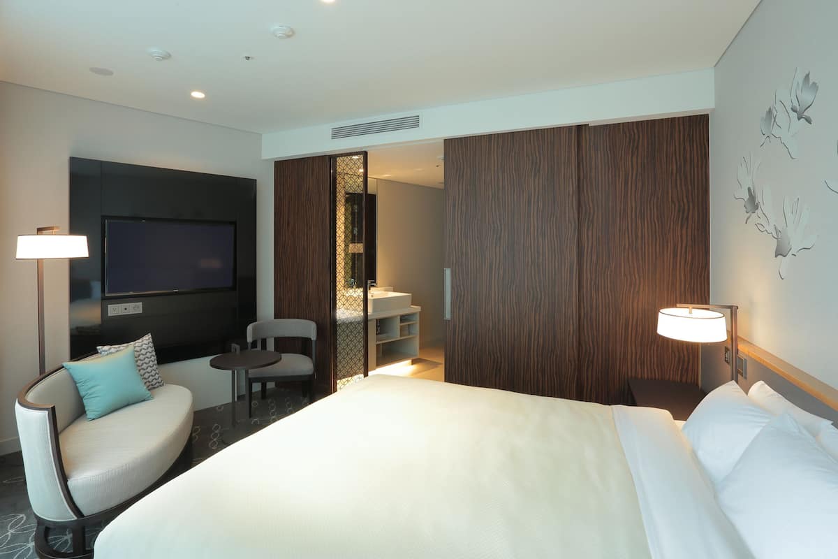 Une chambre d’hôtel avec un grand lit, un bureau, une chaise, une télévision et une salle de bain.