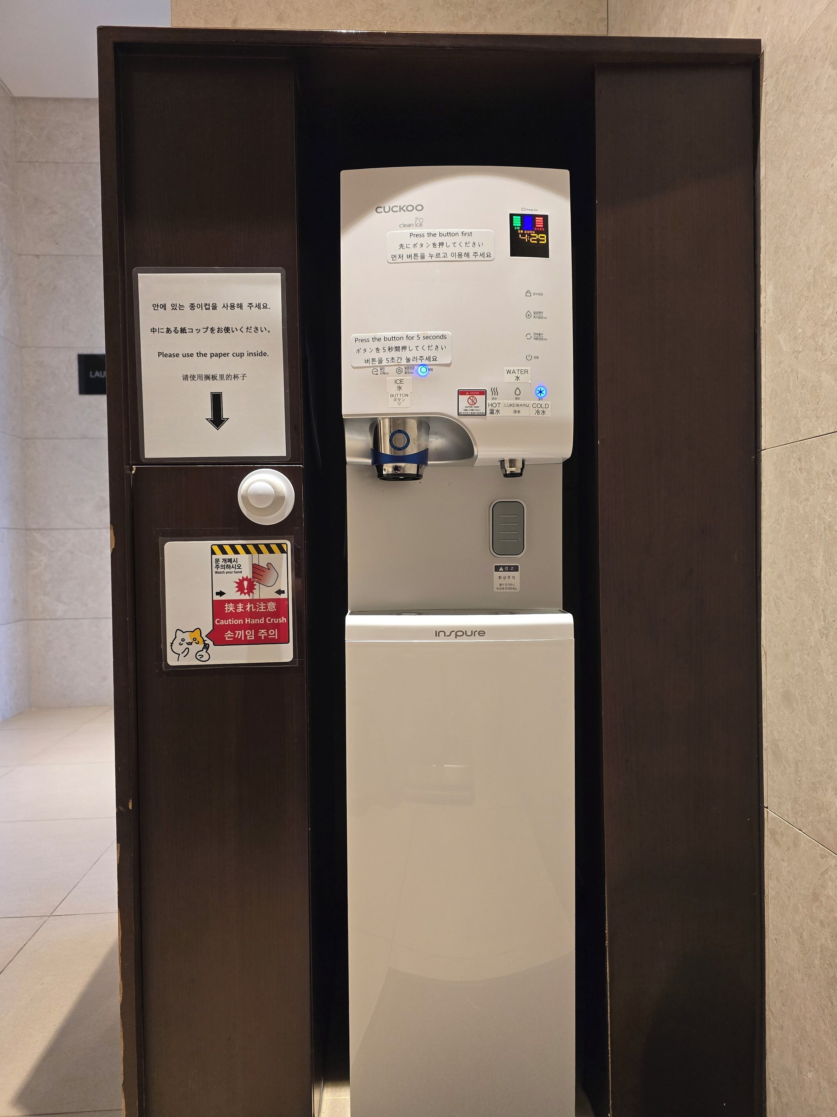 A water dispenser with instructions in multiple languages, a caution hand wash sign, and a control panel with temperature settings.