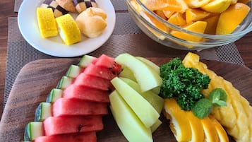 A fruit platter with watermelon, cantaloupe, and oranges on a wooden board.