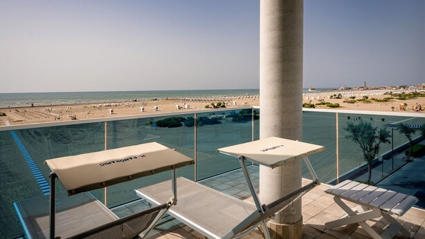 A poolside area with lounge chairs and a view of the beach. - Hotel Panoramic (Caorle)