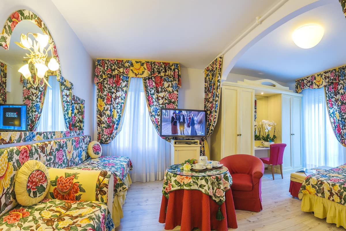 A room with floral-patterned bedding, a television, a desk, and a chair.