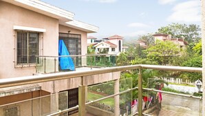 A residential building with a balcony, a covered window, and a view of neighboring houses and greenery. - GuestHouser 2 BHK Bungalow 8619 (Mawal)