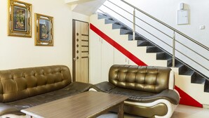 A living room with a sofa, a coffee table, and a staircase with a red accent. - GuestHouser 2 BHK Bungalow 8619 (Mawal)