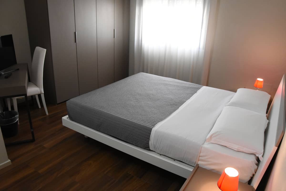 A modern bedroom with a bed, a desk, and a chair.