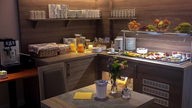 Un bar pour prendre le petit-déjeuner, équipé d’une machine à café, d’un panier de fruits et de divers aliments pour le petit-déjeuner.