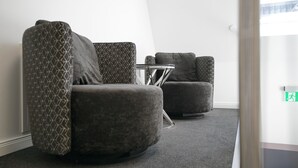 Un espace d’attente moderne avec trois fauteuils gris à revêtement en tissu et une petite table ronde.