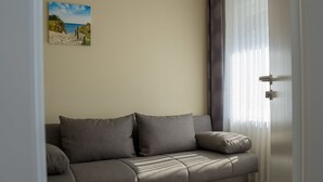 Un canapé aux couleurs neutres dans une pièce dotée d’une fenêtre et d’un tableau au mur.