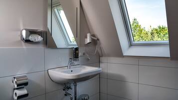 A modern bathroom with a skylight, a sink, a mirror, and a hairdryer.