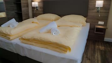 A hotel room with a large bed, two bedside tables, and wall-mounted lamps.