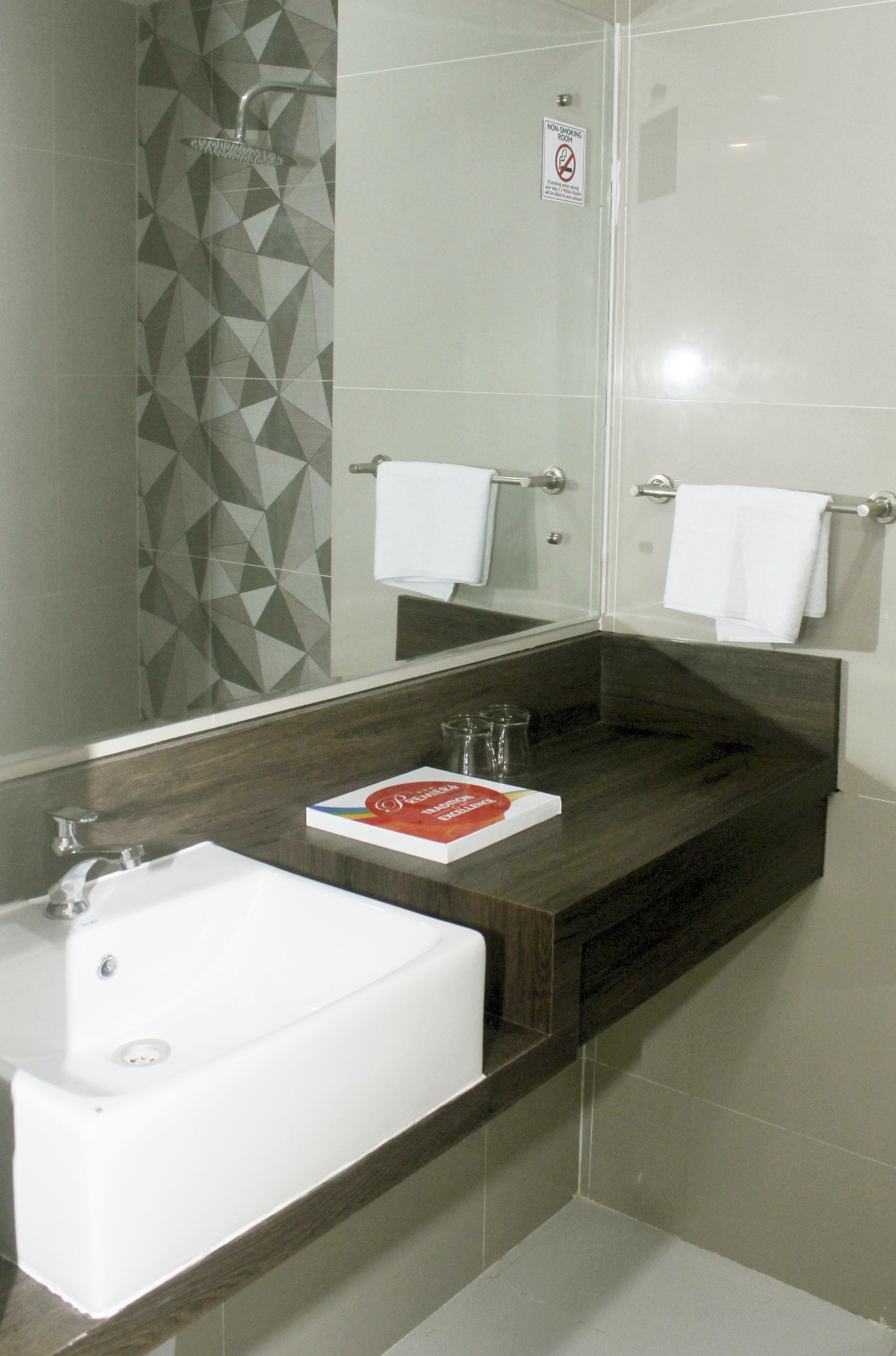 A modern bathroom with a white sink, a glass shower enclosure, and a wooden vanity.