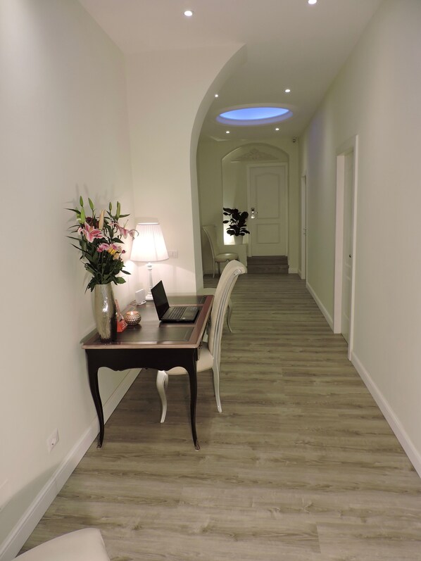 A hallway with a desk, chair, and a laptop.
