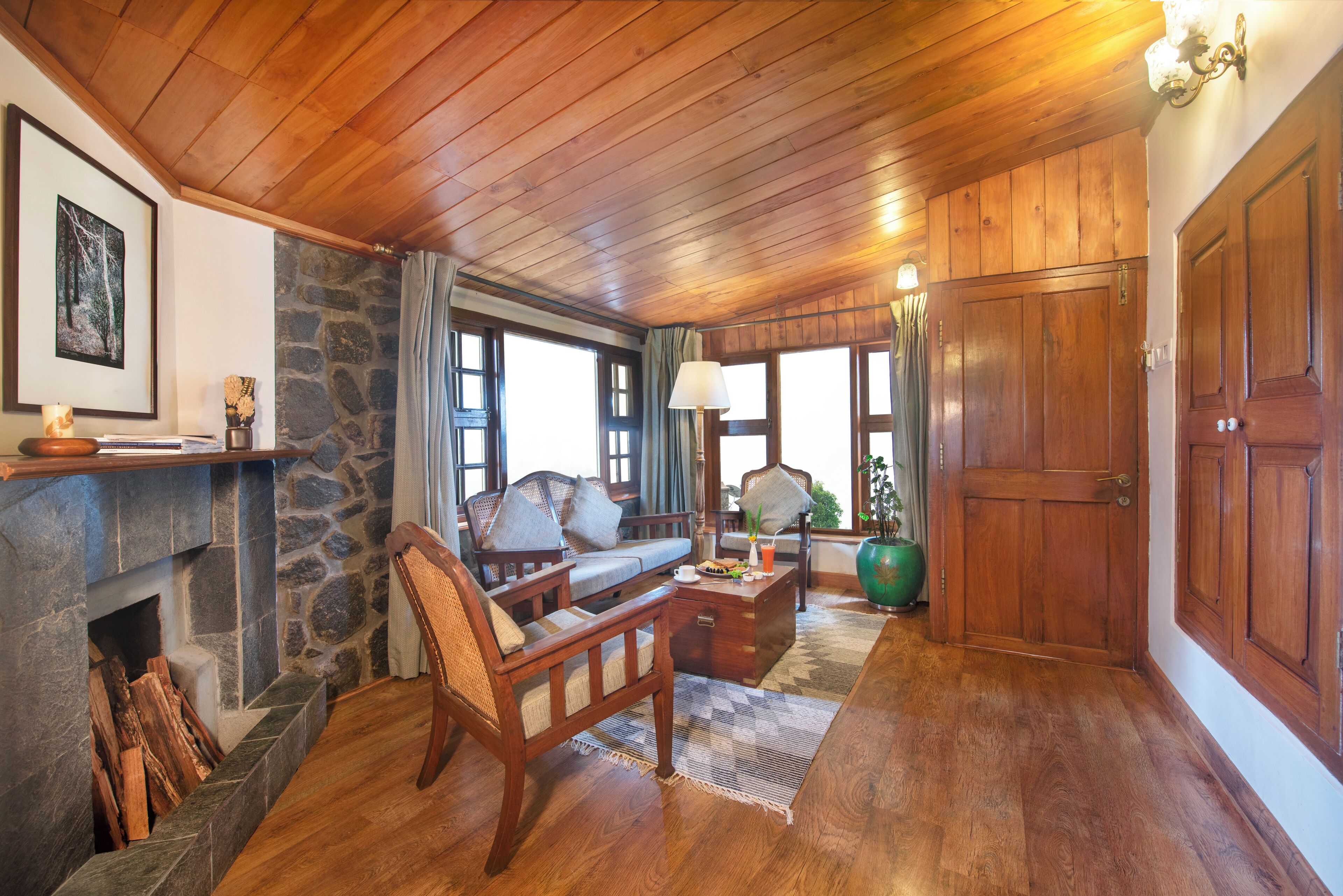 Ein gemütliches Wohnzimmer mit Kamin aus Stein, Holzmöbeln und einer großen Holztür.