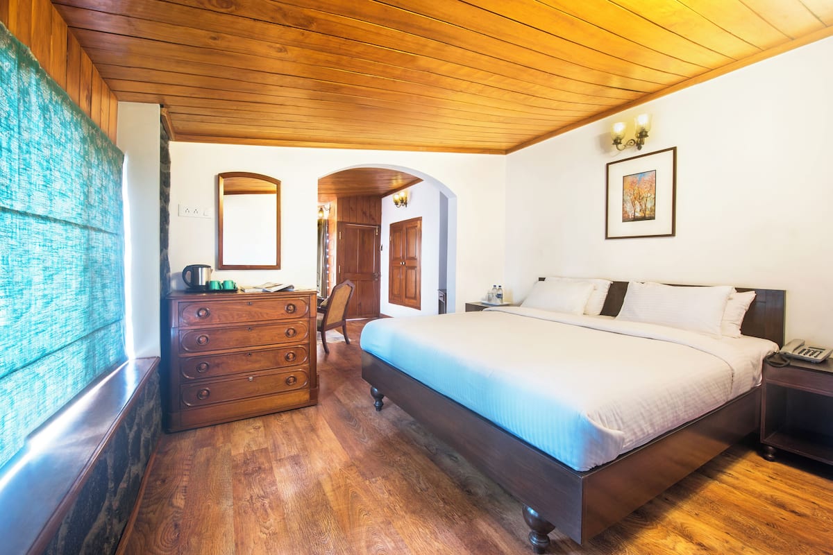 Une chambre avec un plafond en bois, un grand lit, une commode et un miroir.