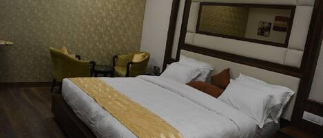 Een hotelkamer met een groot bed, een klein bureau, een stoel en een spiegel aan de muur.
