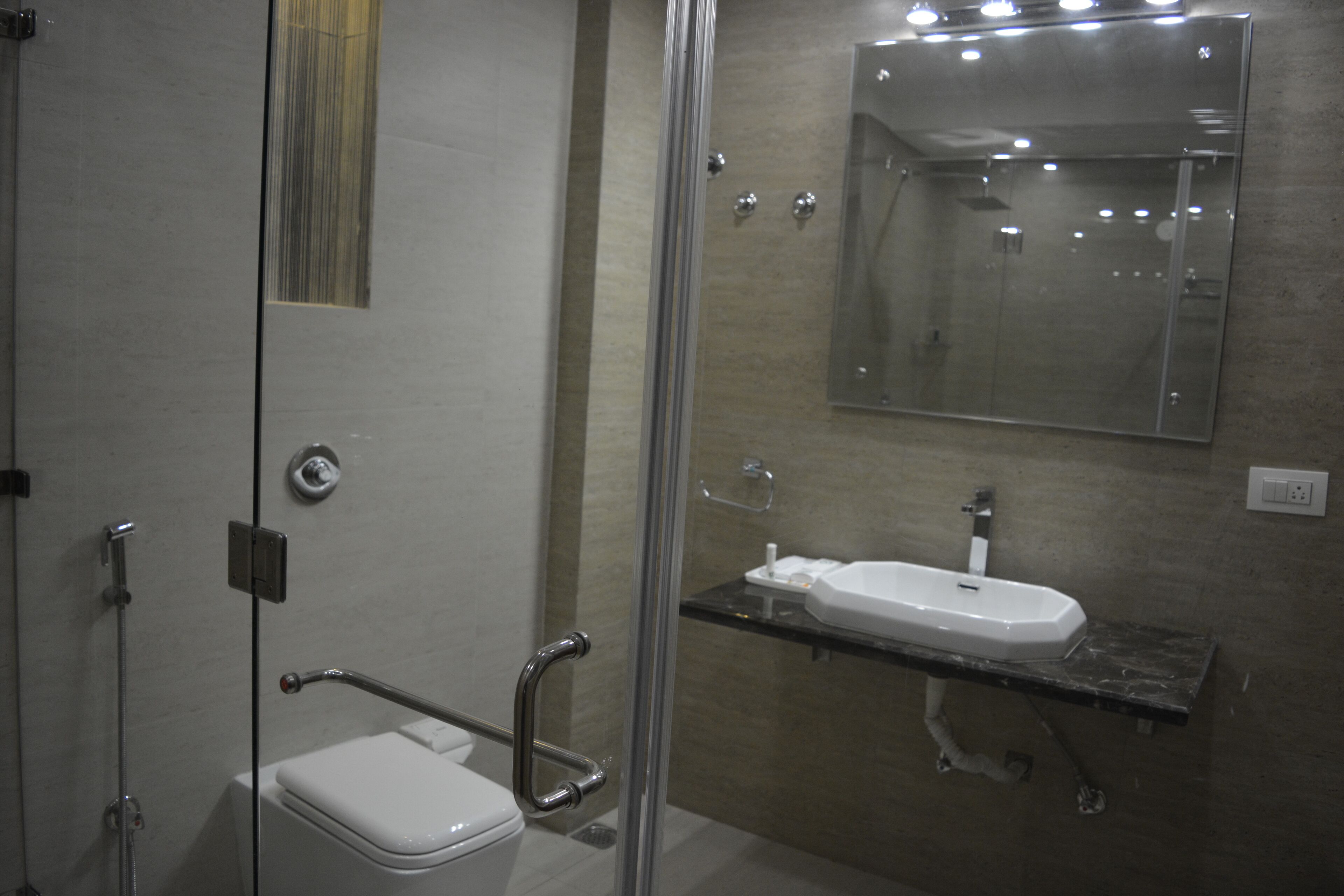 Un baño moderno con cabina de ducha de vidrio, un inodoro blanco y un lavabo con encimera de mármol.