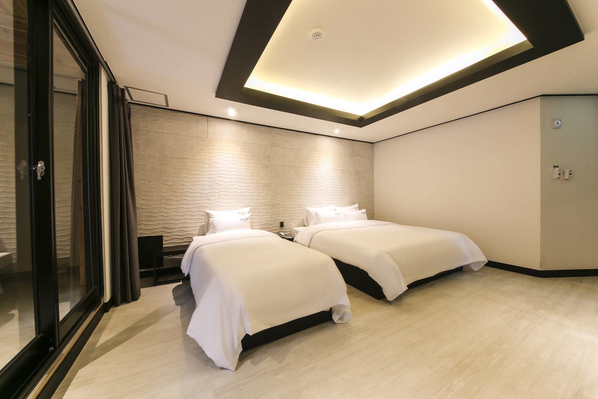 Une chambre d’hôtel moderne avec deux lits, un grand miroir et une armoire.