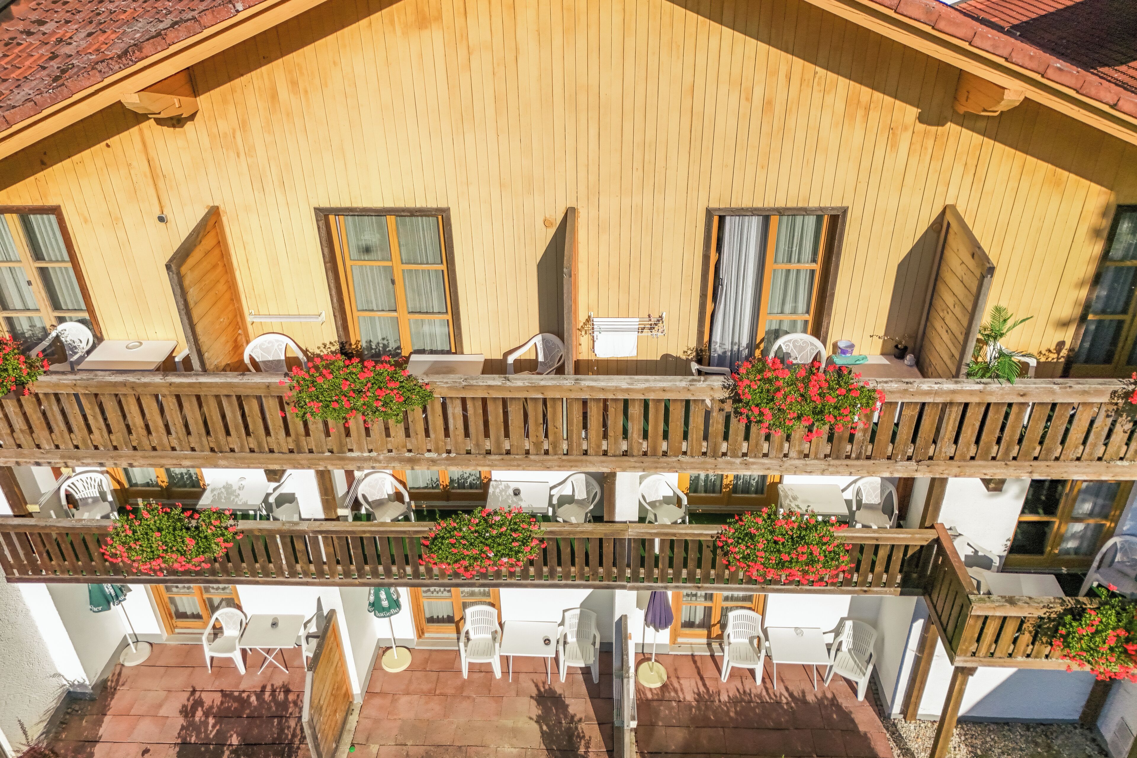 A wooden building with multiple balconies, outdoor seating, and hanging flower baskets.