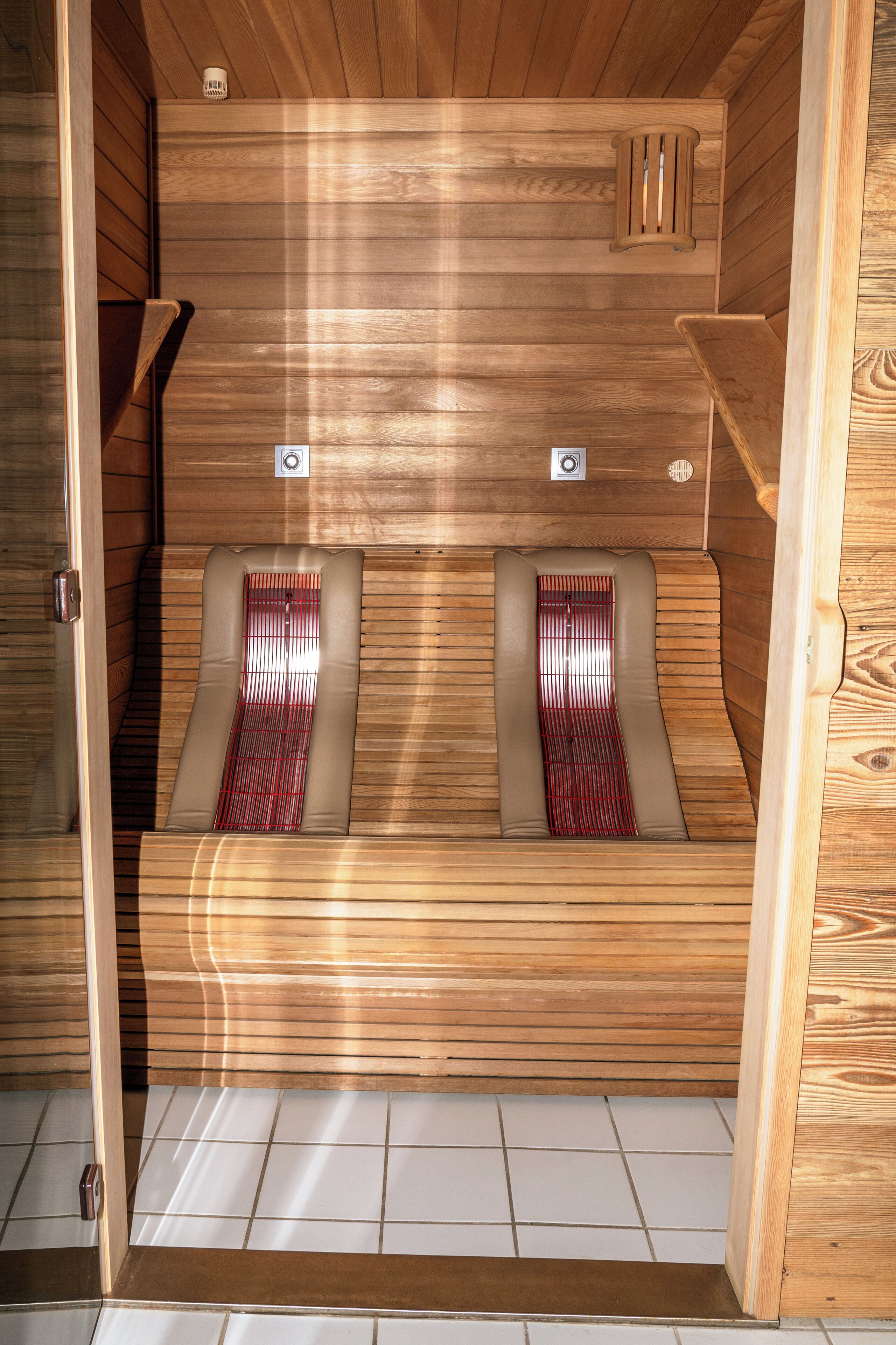 A sauna with two benches, wooden walls, and a tiled floor.