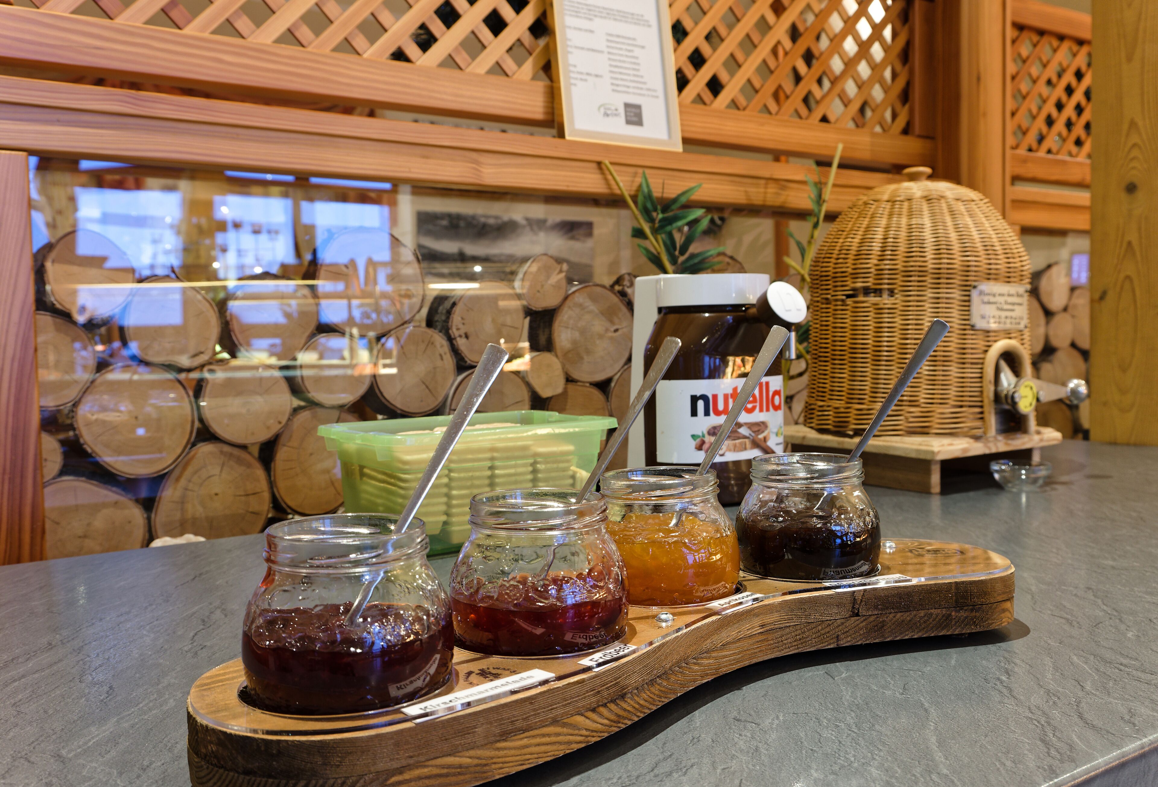 A buffet counter with various jars of preserves and a Nutella dispenser.
