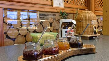 A buffet counter with various jars of preserves and a Nutella dispenser.