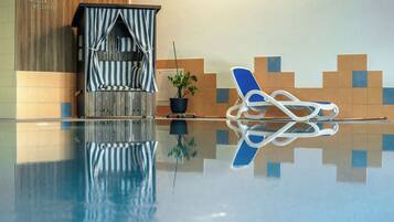 Una piscina nítida amb una cadira de relax i una petita construcció que sembla una casa, amb un teulat a ratlles.