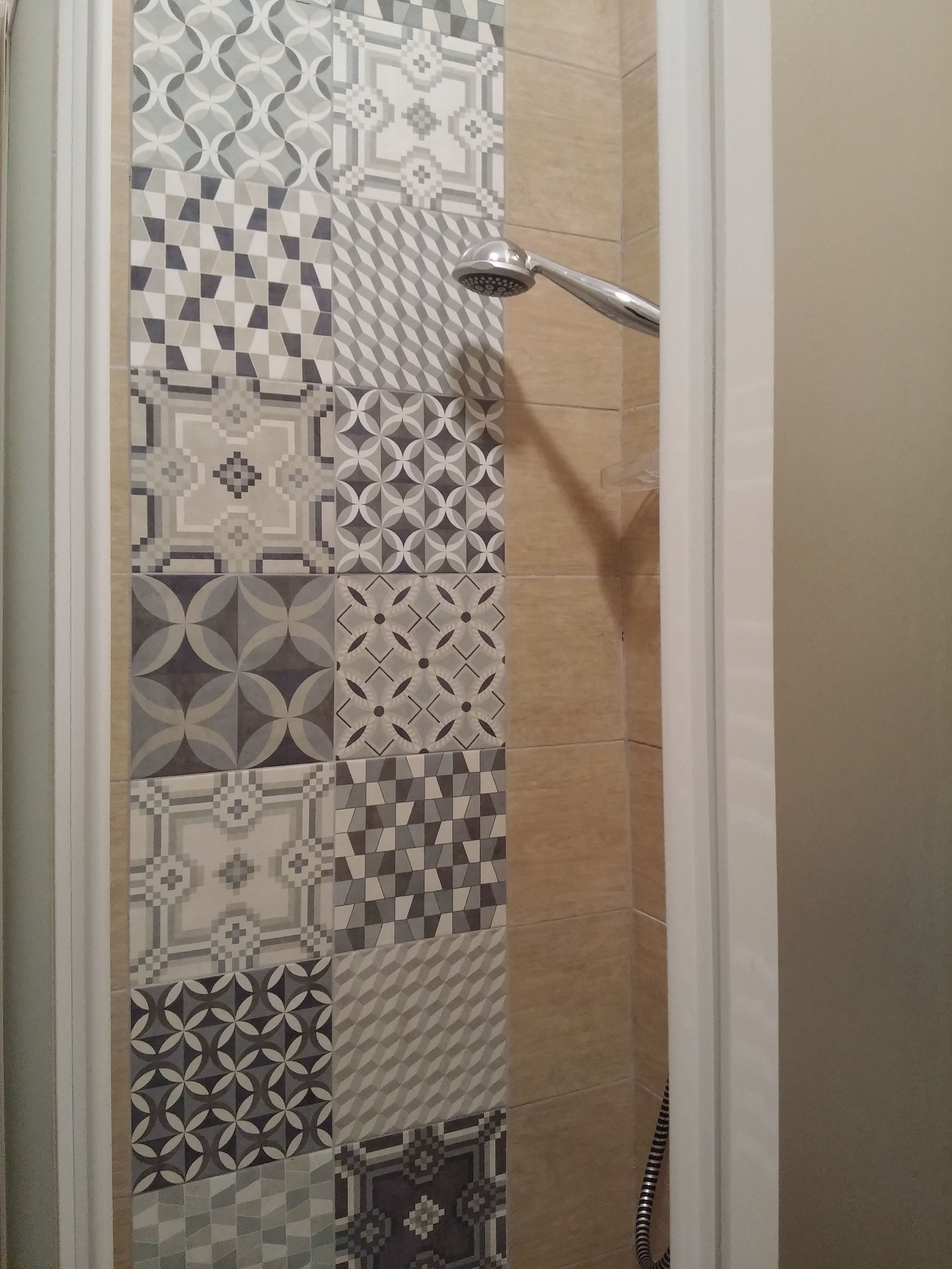 A shower area with a variety of patterned tiles on the walls.