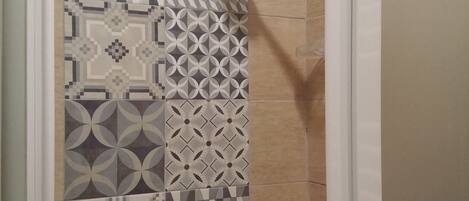 A shower area with a variety of patterned tiles on the walls.