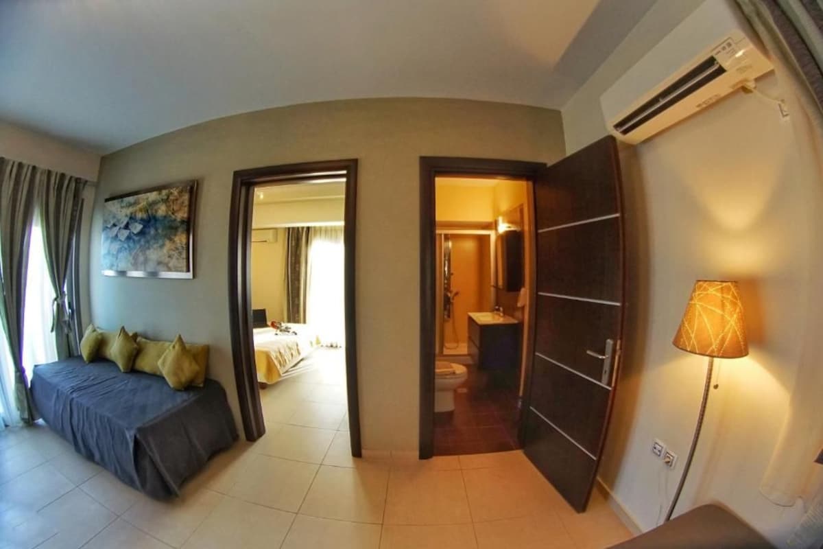 A hotel room with a bed, a desk, a lamp, and an air conditioning unit.