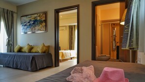 Habitación de hotel con cama, un espejo grande, un cuadro en la pared y un baño visible a través de una puerta abierta.