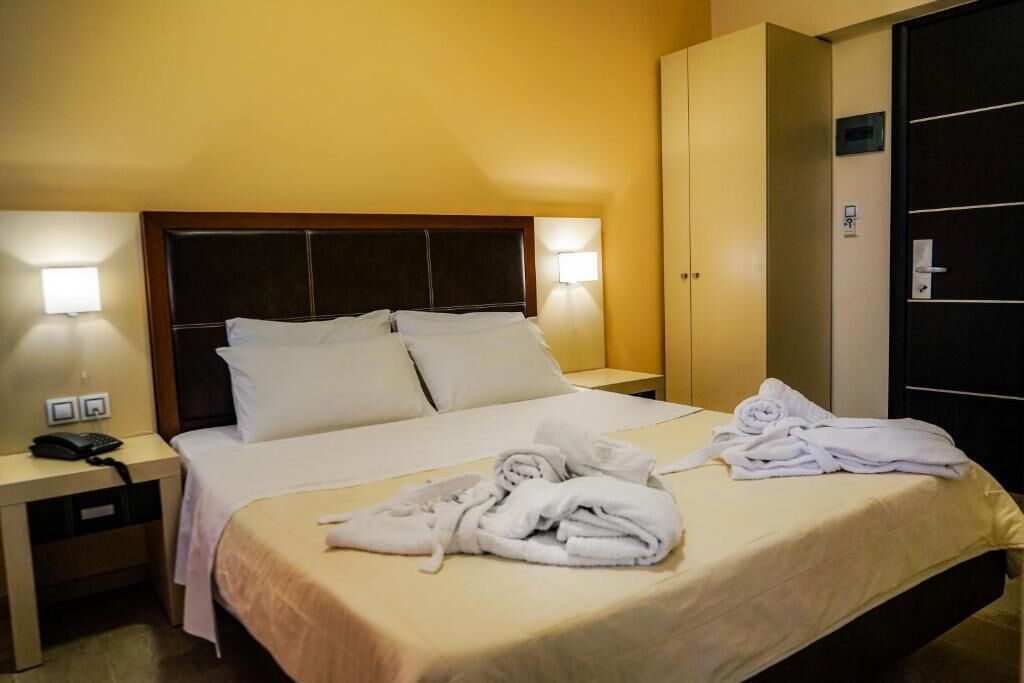Una habitación de hotel con cama, mesitas de noche, armario y teléfono.
