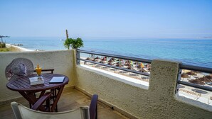 Un balcón con vistas al mar, una mesa con un libro y un vaso, y una silla.