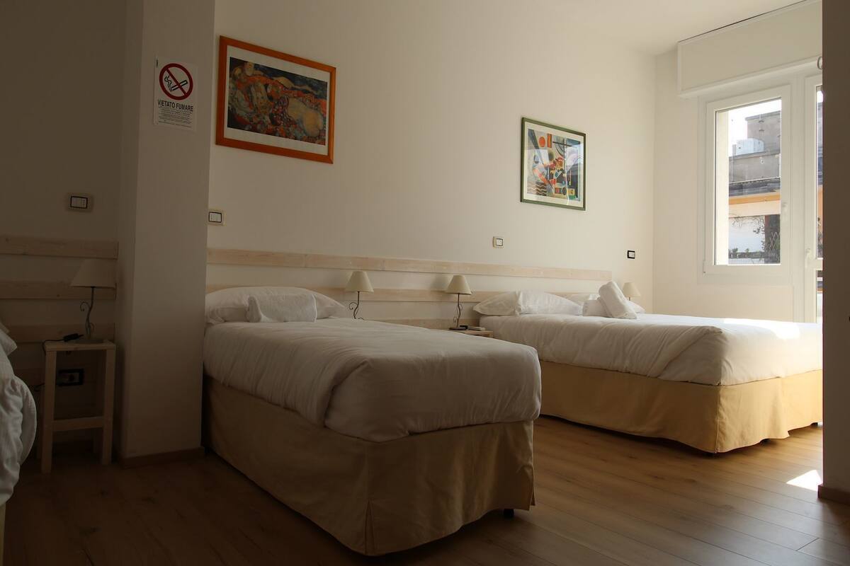 Ein Hotelzimmer mit zwei Betten, einem Fenster und Bildern an den Wänden.