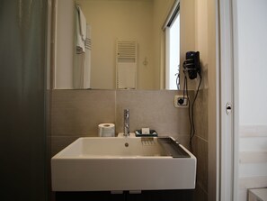 A bathroom with a white sink, a mirror, a towel rack, and a toilet paper dispenser. - La Camera Bologna Stazione Affittaly (Bologna)
