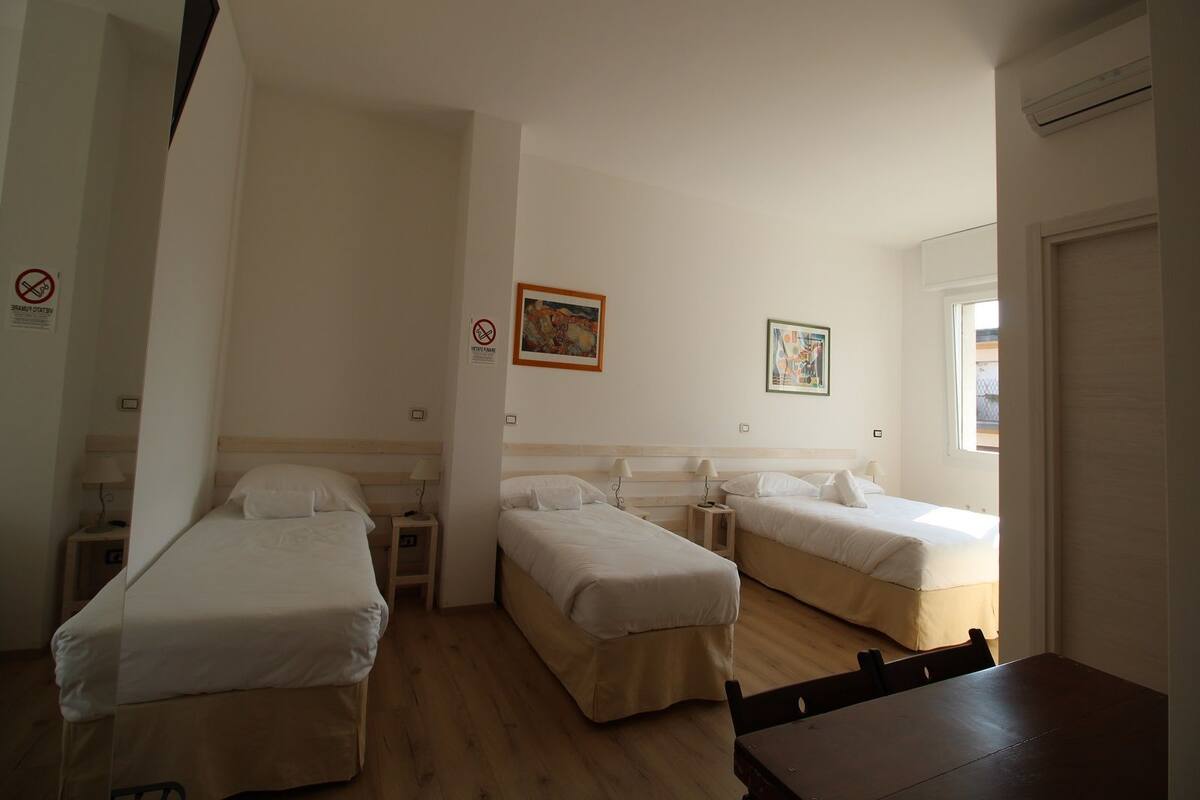 Ein Hotelzimmer mit zwei Einzelbetten, einem Holztisch und einem Fenster.
