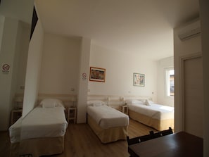 A hotel room with two single beds, a wooden table, and a window. - La Camera Bologna Stazione Affittaly (Bologna)