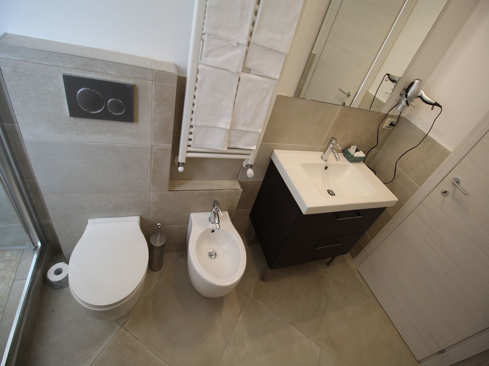 A bathroom with a toilet, bidet, sink, and towel rack.