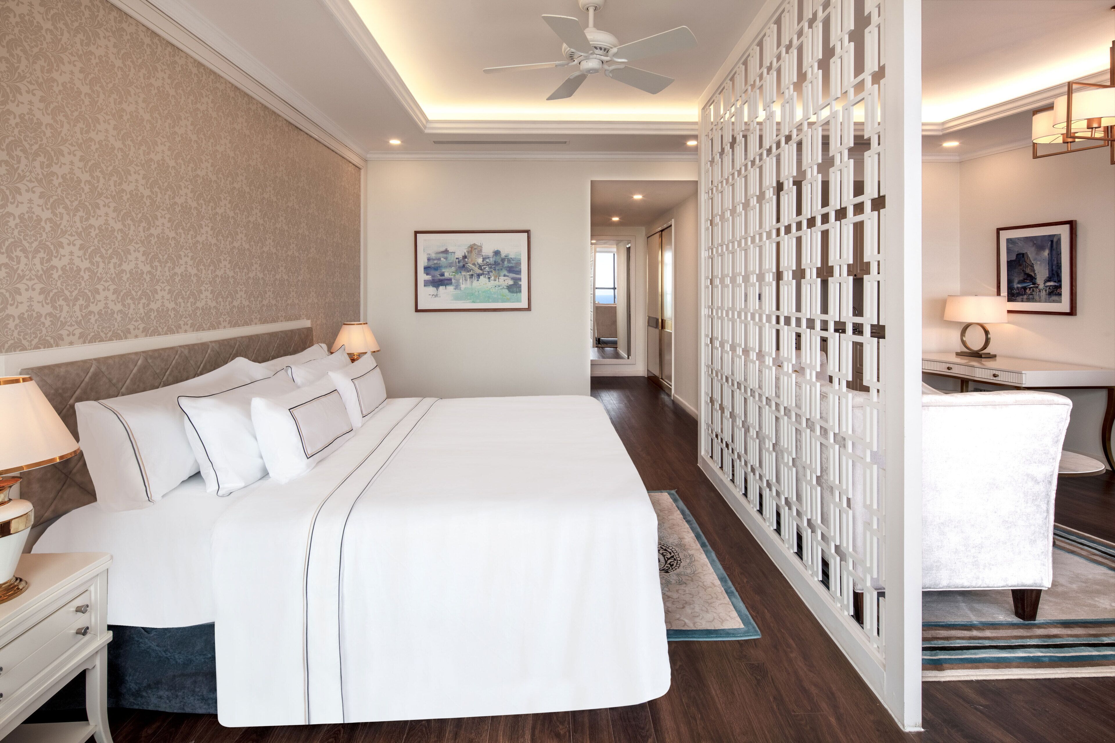 A hotel room with a large bed, bedside tables, a desk, and a view of the hallway.