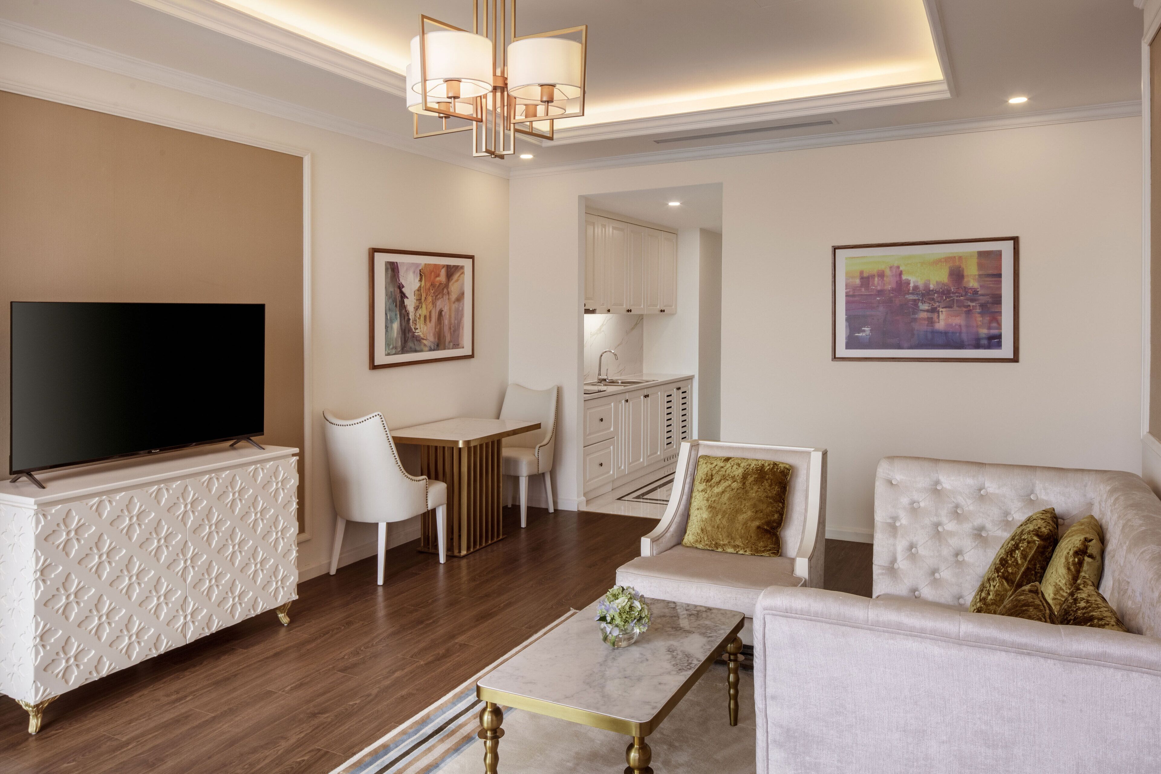 A modern living room with a flat-screen TV, a white sofa, a coffee table, and a dining area with a white table and chairs.