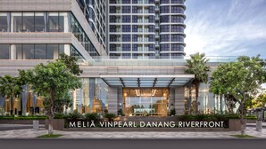 Un hôtel moderne doté d’une entrée imposante, de grandes fenêtres et d’un espace extérieur bien aménagé avec des arbres.