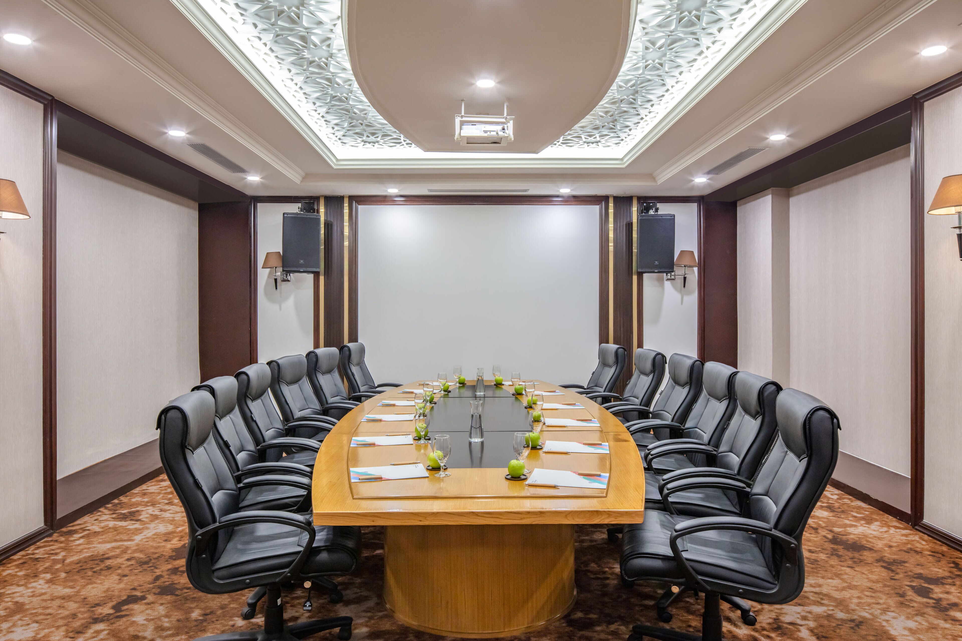 A conference room with a long table, black leather chairs, and a carpeted floor.