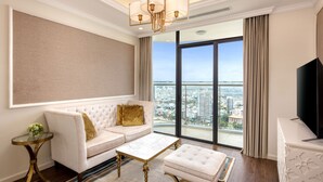 Un salon moderne avec un canapé blanc, une table basse en verre et une grande fenêtre donnant sur la ville.