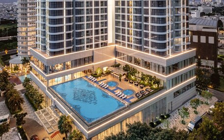 A high-rise hotel with a rooftop pool, multiple balconies, and a well-lit exterior.