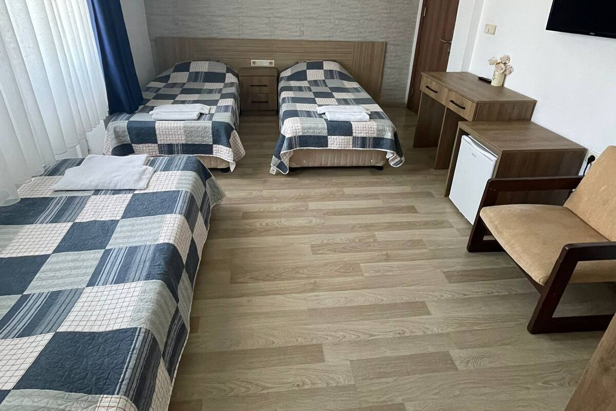 A room with three beds, a desk, a chair, and a TV.