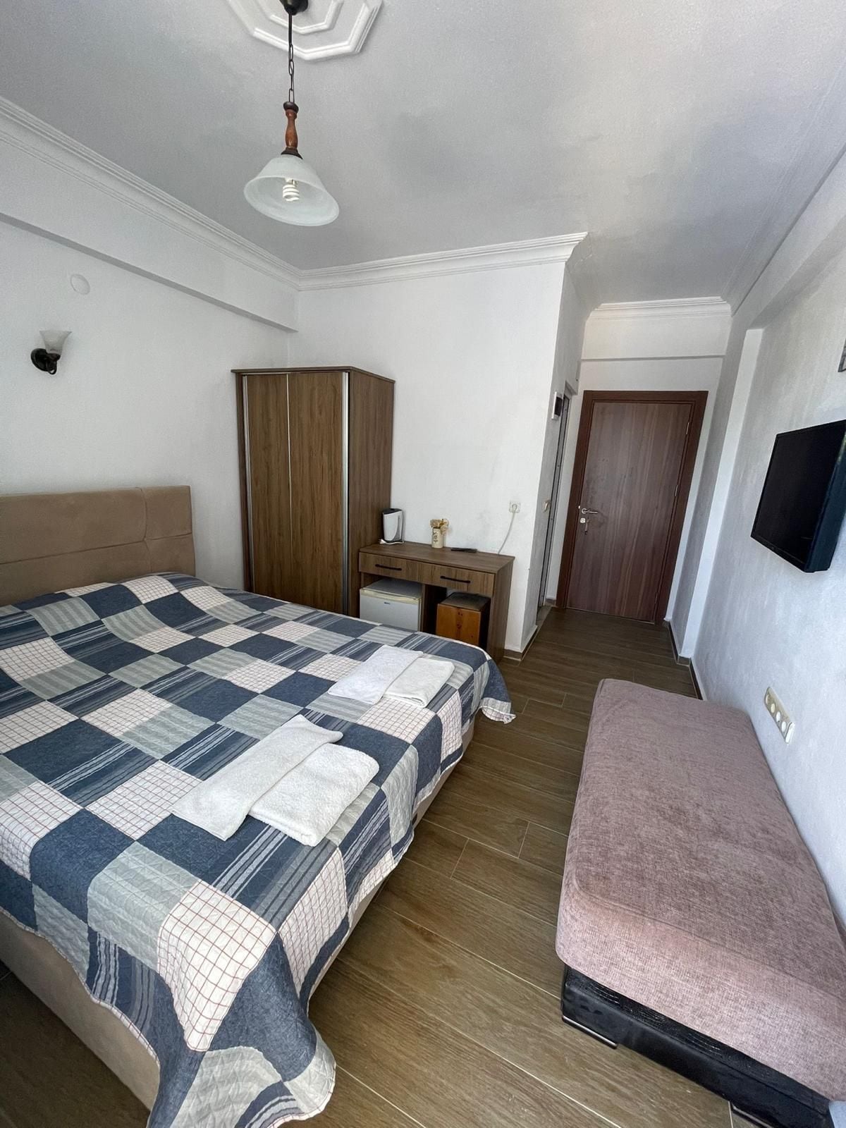 Un dormitorio con cama, escritorio, armario, televisor y banco.