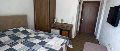 Un dormitorio con cama, escritorio, armario, televisor y banco.