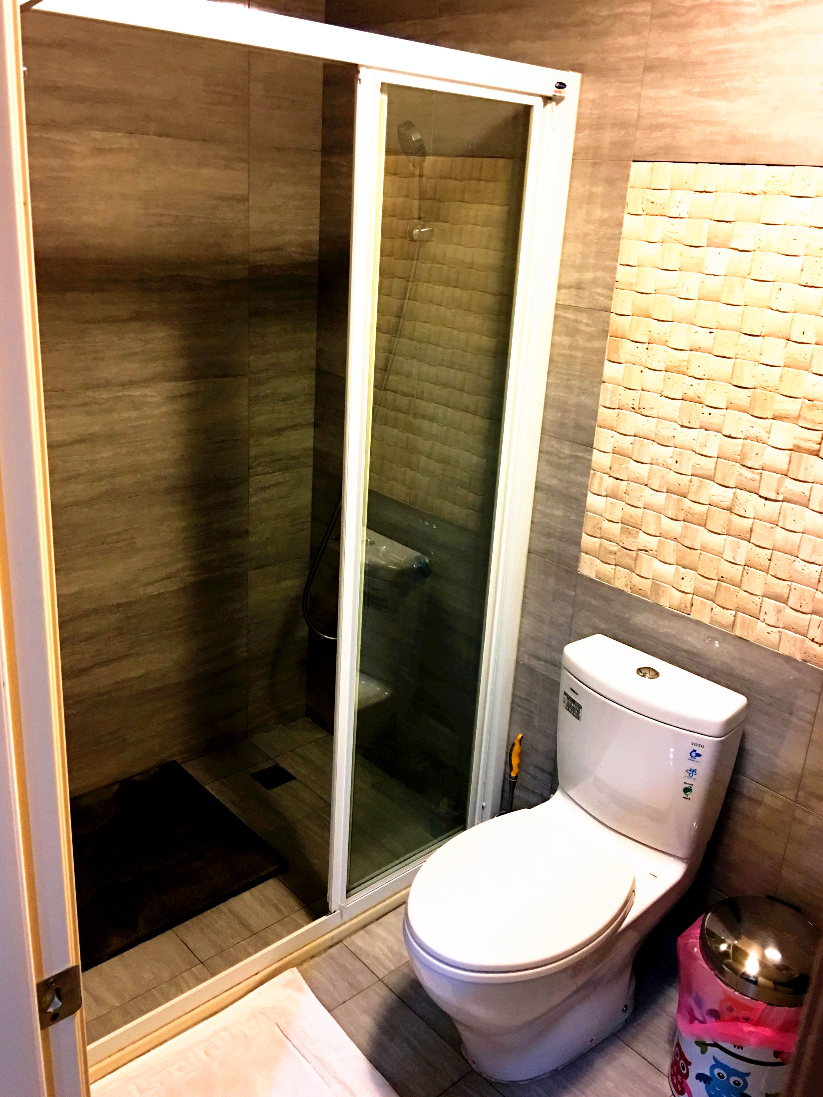 Ein Badezimmer mit einer gläsernen Duschkabine, einer Toilette und einem Mülleimer.