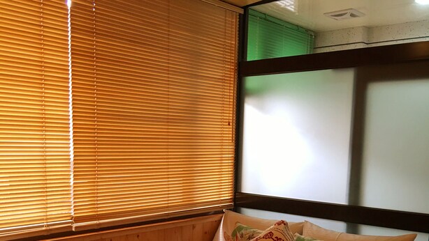 A bed with a patterned bedspread, two pillows, and a window with blinds. - Qi Hua Zhen Ju Homestay (Toucheng)
