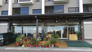 A building with a modern facade, large windows, and a covered entrance area with potted plants. - Qi Hua Zhen Ju Homestay (Toucheng)