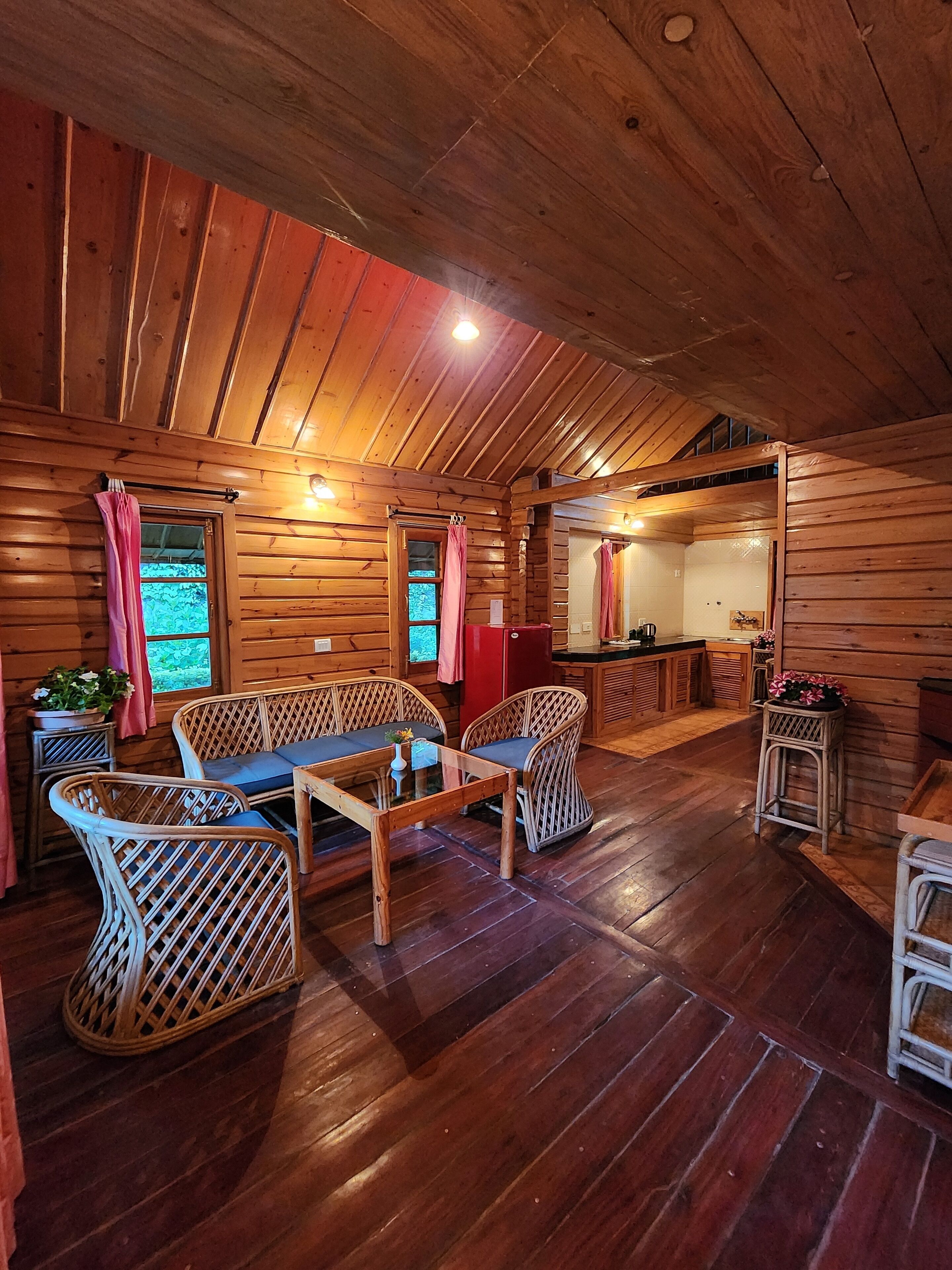 A cozy wooden cabin interior with a dining area, a kitchen, and a bathroom.