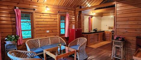 A cozy wooden cabin interior with a dining area, a kitchen, and a bathroom.
